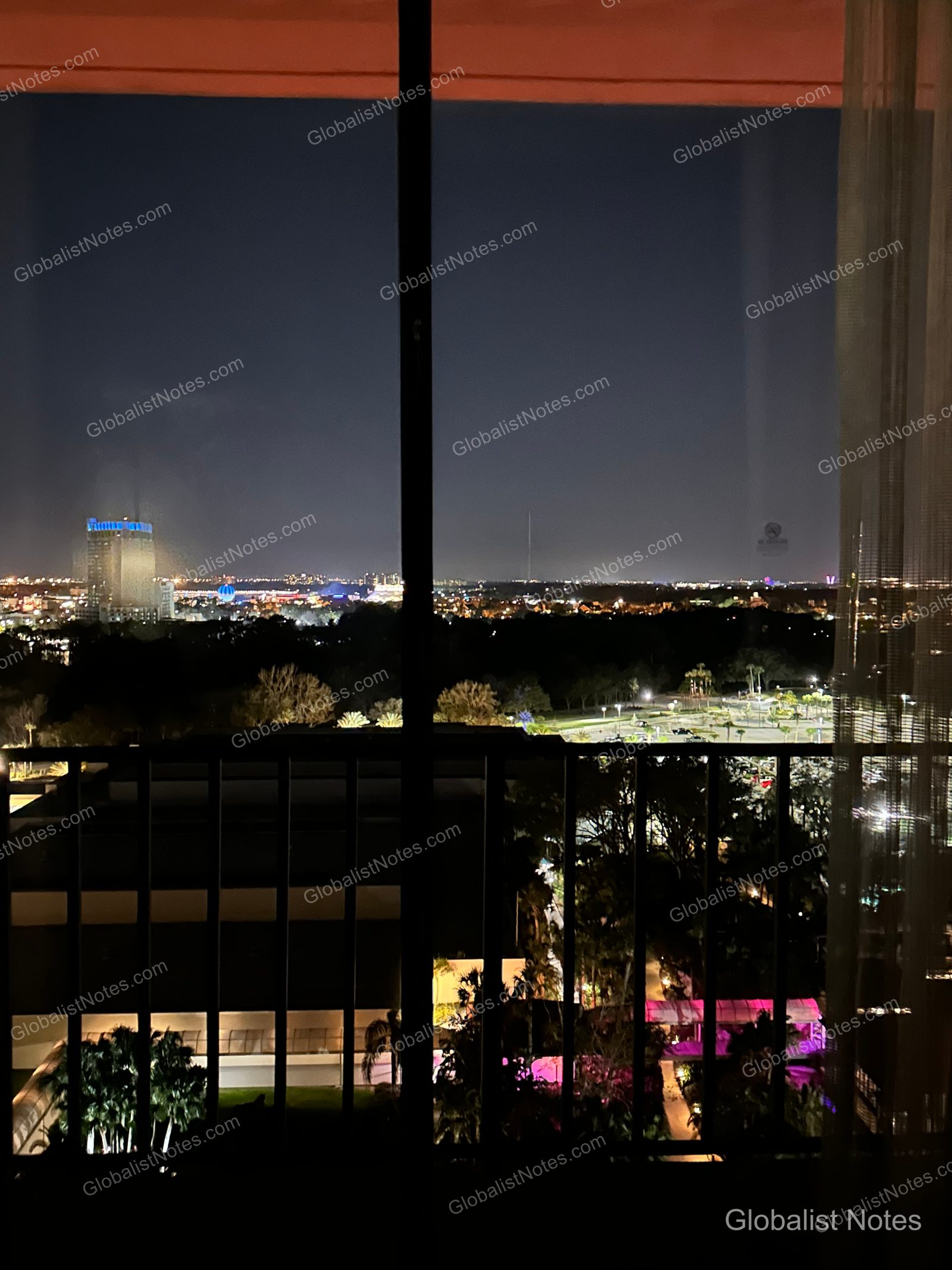 Night view from the balcony of a Standard King room at Hyatt Regency Grand Cypress in Orlando, showing distant city lights and resort lighting under a dark sky.