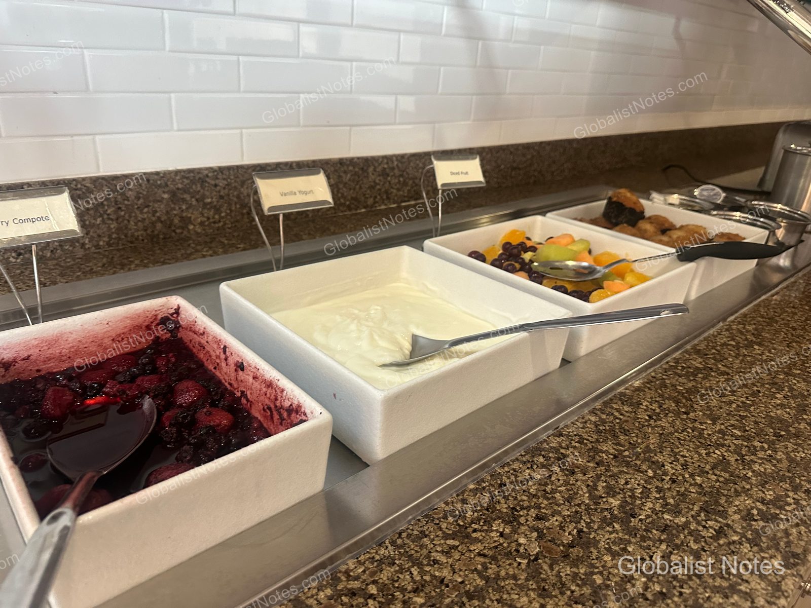 Hyatt House Scottsdale Old Townの朝食ビュッフェ。ベリーコンポート、バニラヨーグルト、フルーツ、ベーカリー類が白い容器に並べられ、メニュー名が記されたプレートが添えられている。