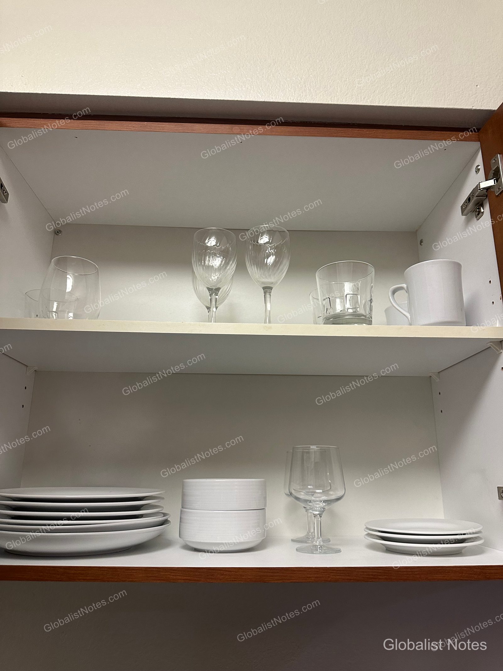 Hyatt House Scottsdale/Old Townの1ベッドルームスイートのキッチン収納。上段にはワイングラスとマグカップ、下段には皿やボウル、グラスが整然と収められています。